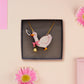An adorable cute goose with a bell and pink bow necklace made of wood and glitter pearlescent acrylic with a gold chain is displayed in a velvet gift box with a unique cute goose sleeve design.