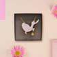 An adorable cute goose with a bell and pink bow necklace made of wood and glitter pearlescent acrylic with a gold chain is displayed in a velvet gift box with a unique cute goose sleeve design.
