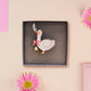 An adorable cute goose with a bell and pink bow brooch pin badge made of wood and glitter pearlescent acrylic with a gold chain is displayed in a velvet gift box with a unique cute goose sleeve design.