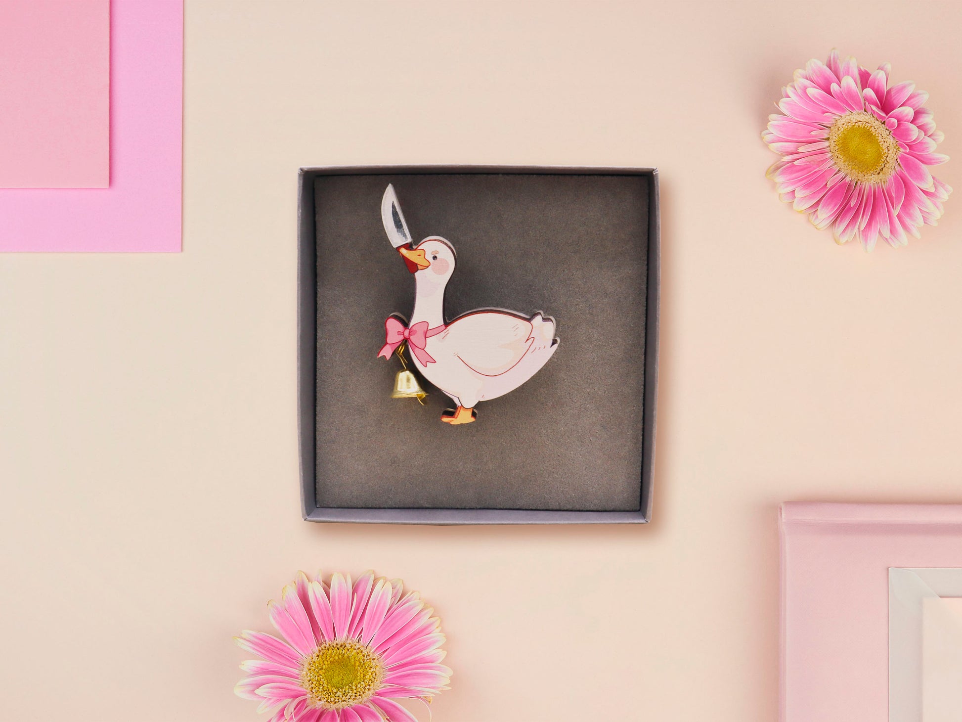 An adorable cute goose with a bell and pink bow brooch pin badge made of wood and glitter pearlescent acrylic with a gold chain is displayed in a velvet gift box with a unique cute goose sleeve design.