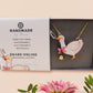 An adorable cute goose with a bell and pink bow necklace made of wood and glitter pearlescent acrylic with a gold chain is displayed in a velvet gift box with a unique cute goose sleeve design.