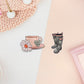 Two stickers of digital illustration cartoons of a cup of tea with glowers and the words a cup of happy and wellington boots with a rain cloud pattern and bow