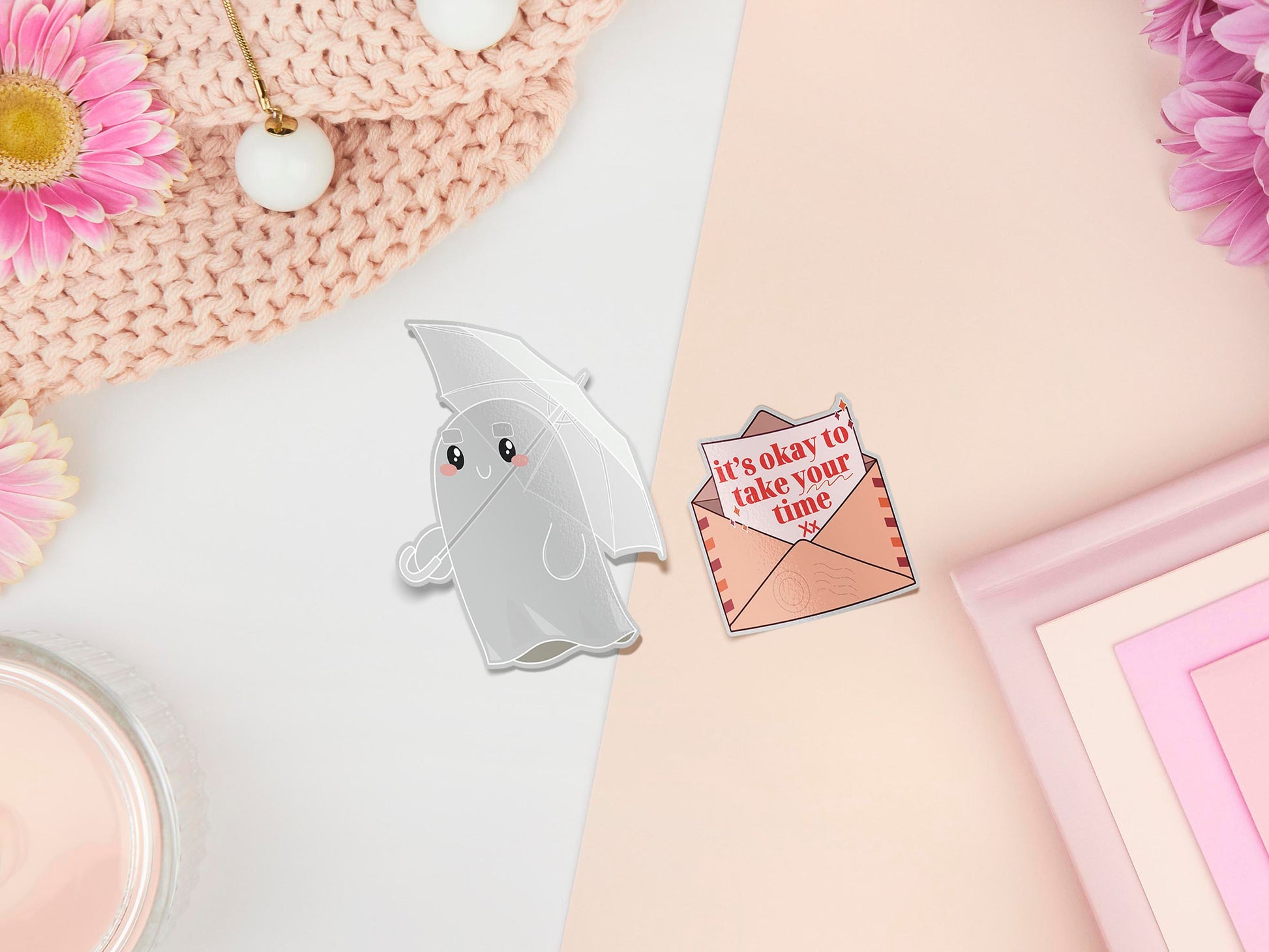 Two stickers of illustrated cartoon ghost with an umbrella and a letter in an envelope that reads it's okay to take your time 