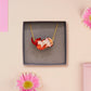 An adorable cute otter holding a clam seashell with a pearl inside necklace made of wood and glitter pearlescent acrylic with a gold chain is displayed in a velvet gift box with a unique cute otter sleeve design.