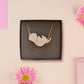 An adorable cute otter holding a clam seashell with a pearl inside necklace made of wood and glitter pearlescent acrylic with a gold chain is displayed in a velvet gift box with a unique cute otter sleeve design.