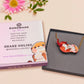 An adorable cute otter holding a clam seashell with a pearl inside necklace made of wood and glitter pearlescent acrylic with a gold chain is displayed in a velvet gift box with a unique cute otter sleeve design.
