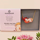 An adorable cute otter holding a clam seashell with a pearl inside necklace made of wood and glitter pearlescent acrylic with a gold chain is displayed in a velvet gift box with a unique cute otter sleeve design.