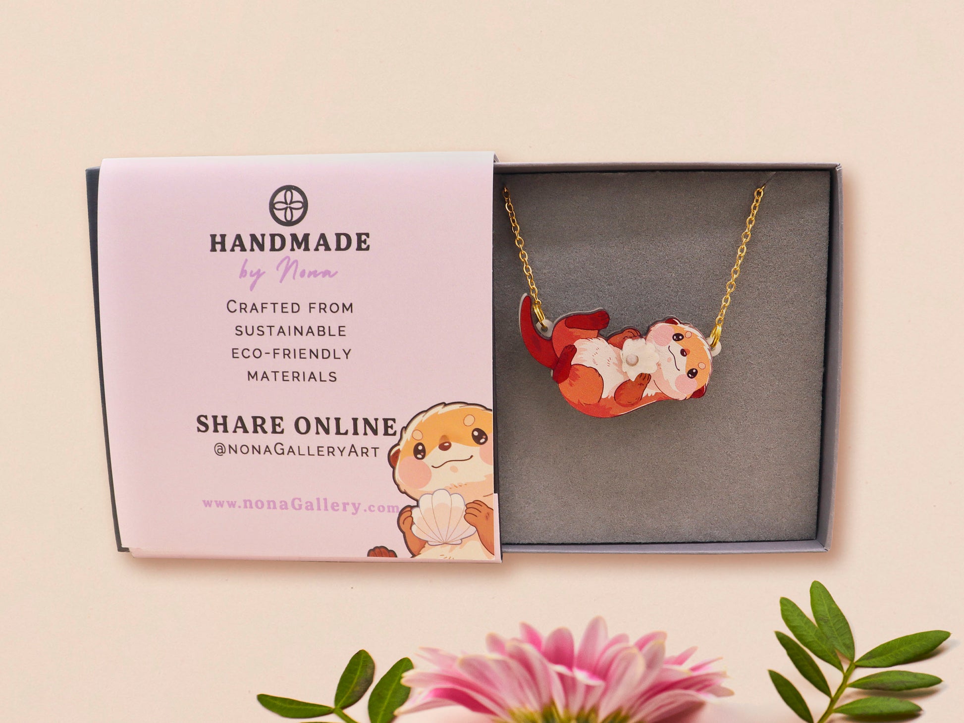 An adorable cute otter holding a clam seashell with a pearl inside necklace made of wood and glitter pearlescent acrylic with a gold chain is displayed in a velvet gift box with a unique cute otter sleeve design.