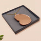 An adorable shy pangolin aardvark holding a heart necklace made of wood and glitter mirror acrylic with a gold chain is displayed in a velvet gift box with a unique cute Pangolin sleeve design.