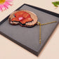 An adorable shy pangolin aardvark holding a heart necklace made of wood and glitter mirror acrylic with a gold chain is displayed in a velvet gift box with a unique cute Pangolin sleeve design.