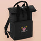 Black roll top backpack with a front pocket and an embroided mimic chest face cryptid design with the text *definetley not a mimic