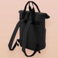 Black roll top backpack with a front pocket and an embroided mimic chest face cryptid design with the text *definetley not a mimic