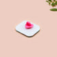 A clear acrylic pin badge with a pink heart-shaped pin back clasp. The design of the pin badge is of a cute relaxing capybara in water with a face mask with the quote don't worry be cappy.