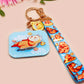 Acrylic epoxy blue capybara spa keychain with a large acrylic charm of a capybara floating in water relaxing with a face mask with the quote don't worry be cappy, a smaller charm of a cute rubber duck and a matching capybara spa day lanyard.