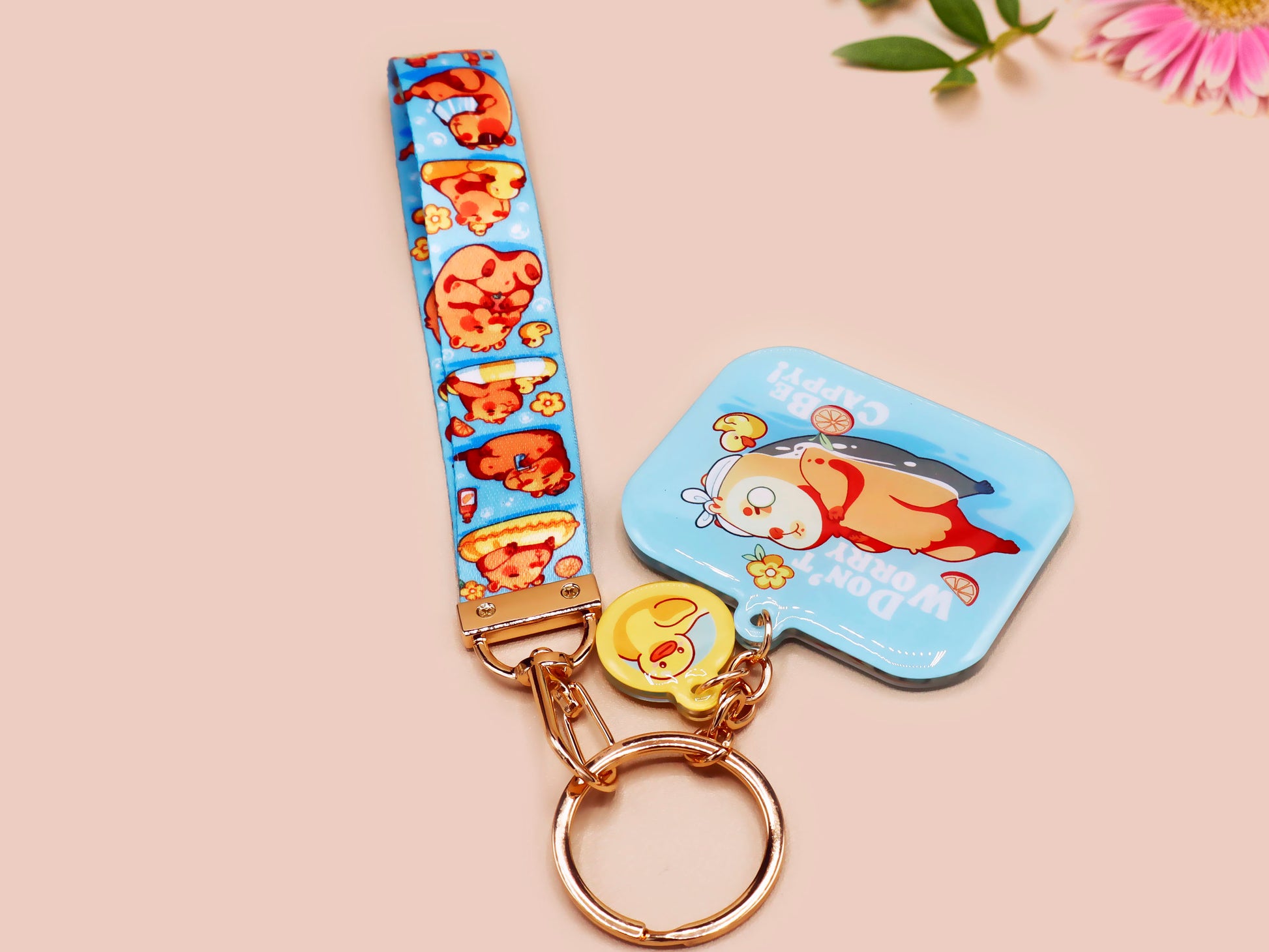 Acrylic epoxy blue capybara spa keychain with a large acrylic charm of a capybara floating in water relaxing with a face mask with the quote don't worry be cappy, a smaller charm of a cute rubber duck and a matching capybara spa day lanyard.