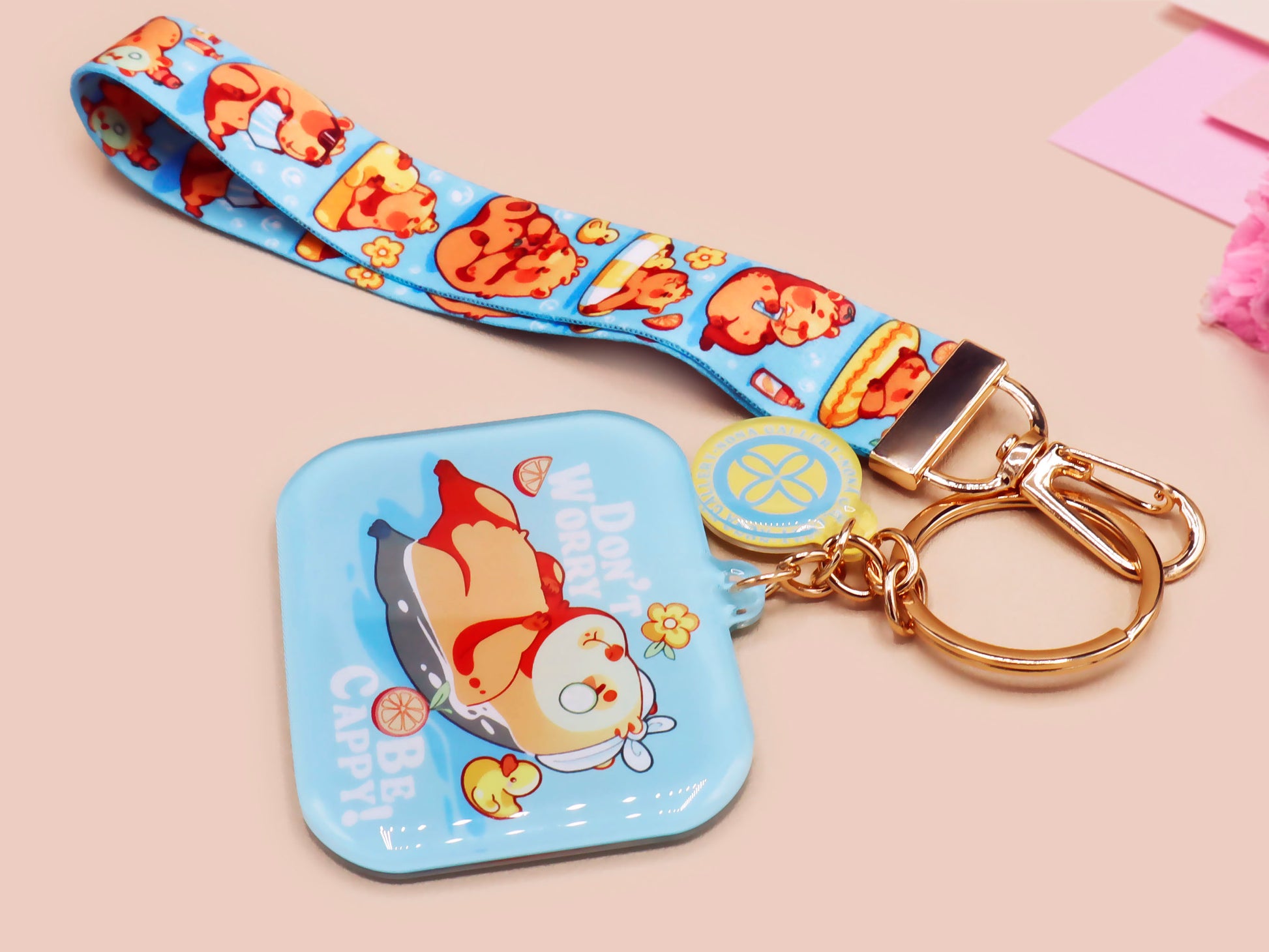 Acrylic epoxy blue capybara spa keychain with a large acrylic charm of a capybara floating in water relaxing with a face mask with the quote don't worry be cappy, a smaller charm of a cute rubber duck and a matching capybara spa day lanyard.