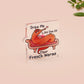 A cute transparent acrylic pin badge with a pink heart-shaped rubber clasp pin back. The design of the pin badge is a cartoon orange worm on a sting sitting on a sofa chaise lounge with the titanic quote Draw Me Like One of Your French Worms