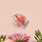 A cute transparent acrylic pin badge with a pink heart-shaped rubber clasp pin back. The design of the pin badge is a cartoon orange worm on a sting sitting on a sofa chaise lounge with the titanic quote Draw Me Like One of Your French Worms