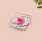 A cute transparent acrylic pin badge with a pink heart-shaped rubber clasp pin back. The design of the pin badge is a cartoon orange worm on a sting sitting on a sofa chaise lounge with the titanic quote Draw Me Like One of Your French Worms