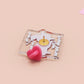 A cute transparent acrylic pin badge with a pink heart-shaped rubber clasp pin back. The design of the pin badge is a cartoon orange worm on a sting sitting on a sofa chaise lounge with the titanic quote Draw Me Like One of Your French Worms
