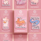 A cute transparent acrylic pin badge with a pink heart-shaped rubber clasp pin back. The design of the pin badge is a cartoon orange worm on a sting sitting on a sofa chaise lounge with the titanic quote Draw Me Like One of Your French Worms