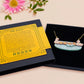 A wooden and glitter acrylic necklace with gold chain in a black box of a cute family of ducks two adult white ducks and four yellow ducklings playing and splashing in the water