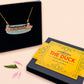 A wooden and glitter acrylic necklace with gold chain in a black box of a cute family of ducks two adult white ducks and four yellow ducklings playing and splashing in the water