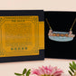 A wooden and glitter acrylic necklace with gold chain in a black box of a cute family of ducks two adult white ducks and four yellow ducklings playing and splashing in the water
