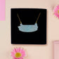 A wooden and glitter acrylic necklace with gold chain in a black box of a cute family of ducks two adult white ducks and four yellow ducklings playing and splashing in the water