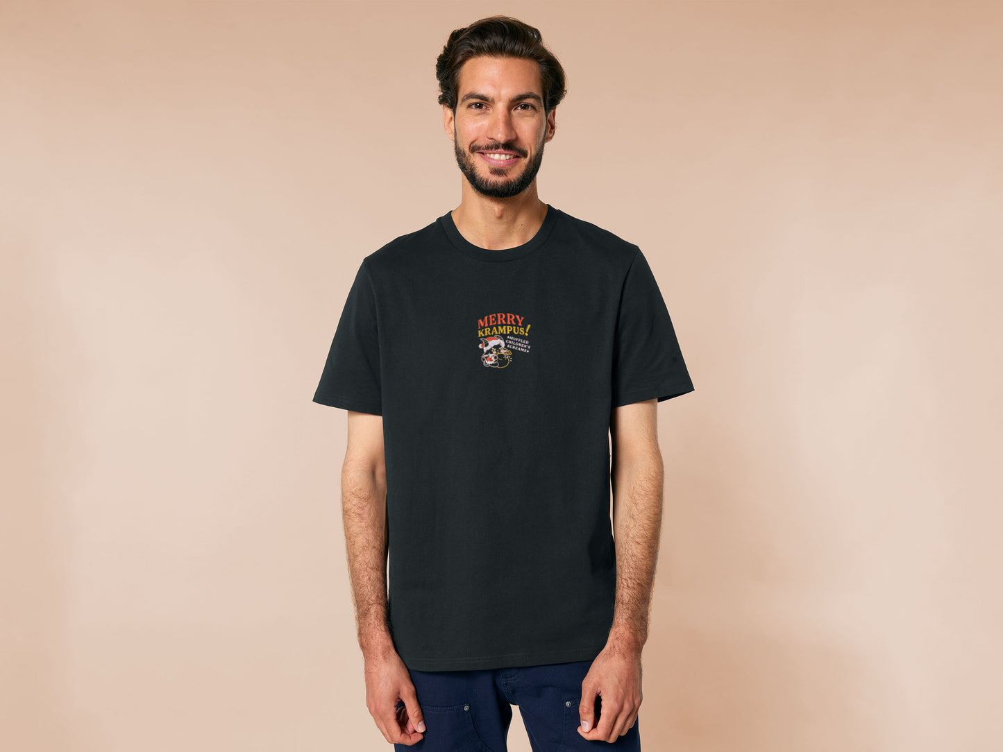 A black crew neck short sleeve tshirt, with an embroidered chibi krampus christmas demon holdign a sack and the quote Mery Krampus! Muffled Children's screams
