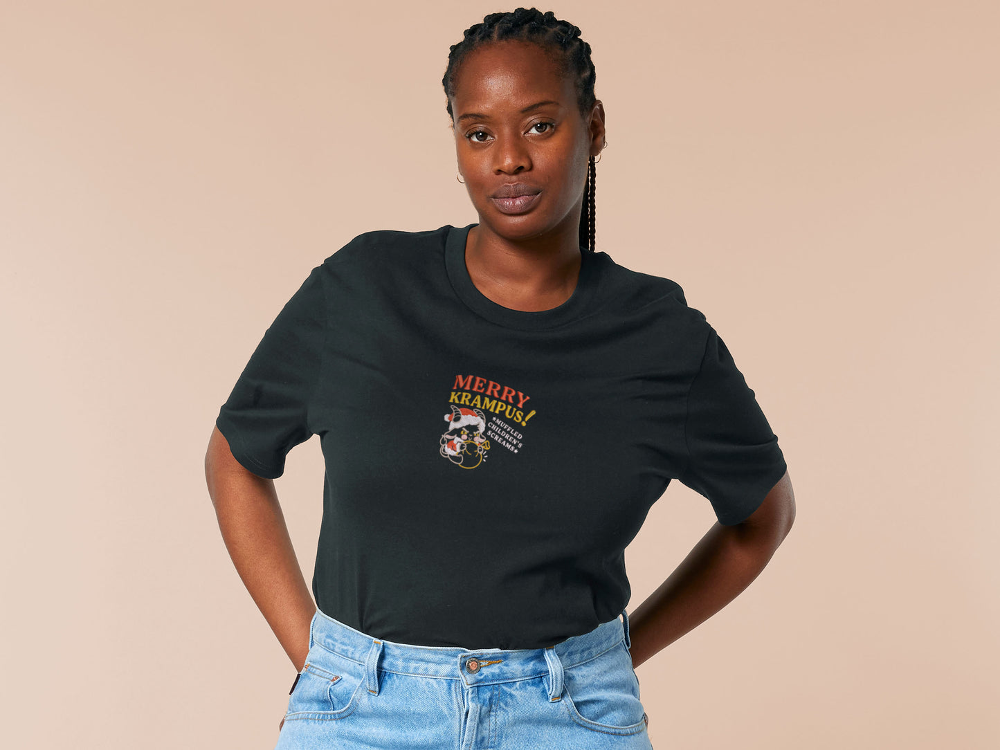 A black crew neck short sleeve tshirt, with an embroidered chibi krampus christmas demon holdign a sack and the quote Mery Krampus! Muffled Children's screams