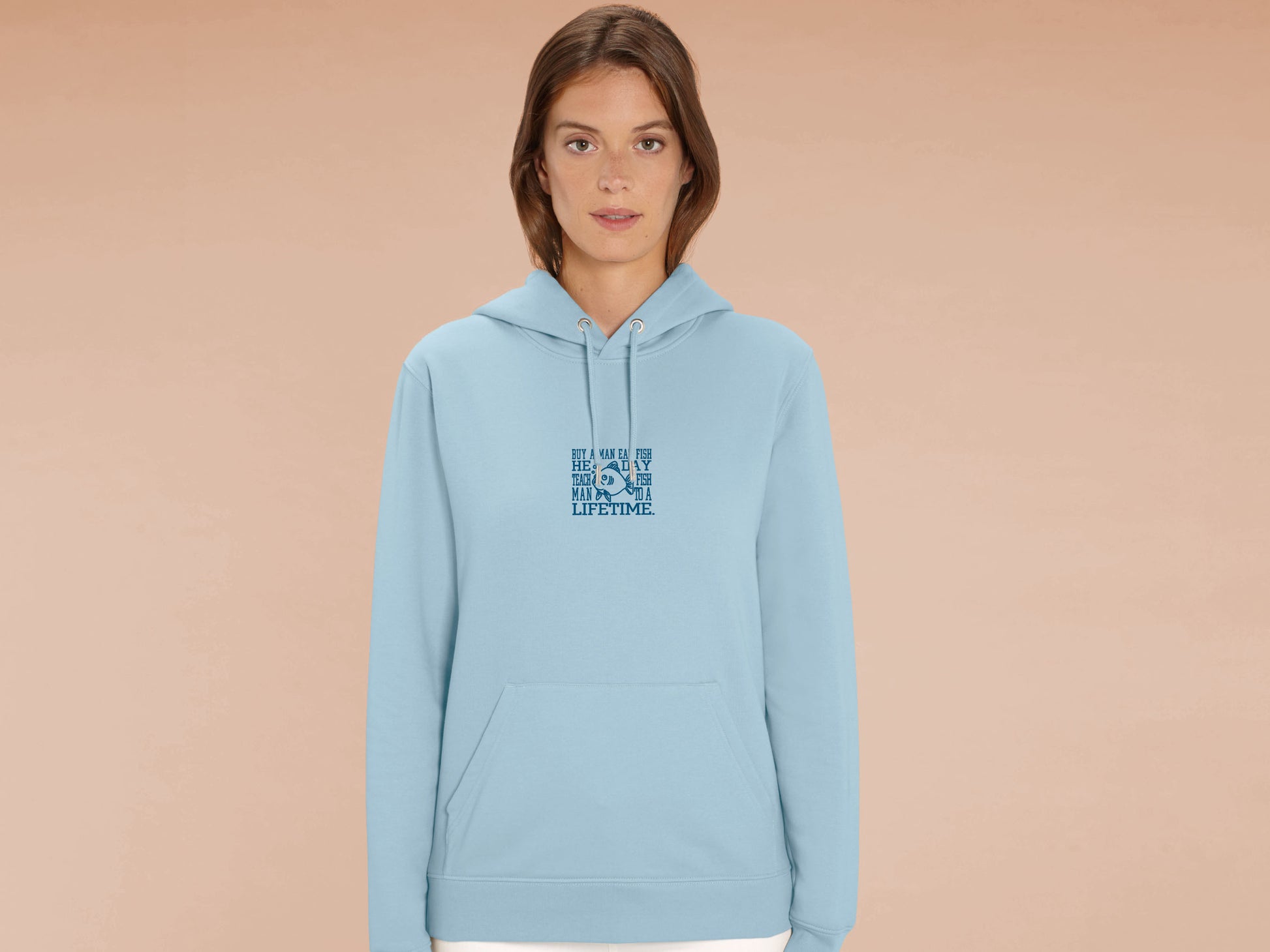 A woman wearing a blue long sleeved fleece hoodie with an embroidered blue design of a cartoon funny fish with the meme text Buy a man eat a fish he day teach fish man to a lifetime.