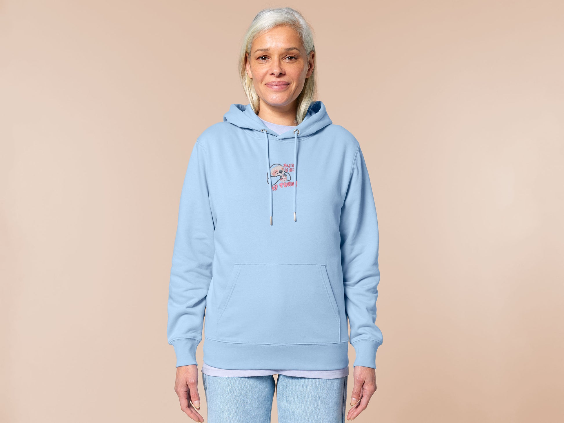A blue hoodie with an embroidered design of a cute chibi sloth holiding a board game dice surrounded by the funny quote Yes it is still my turn!