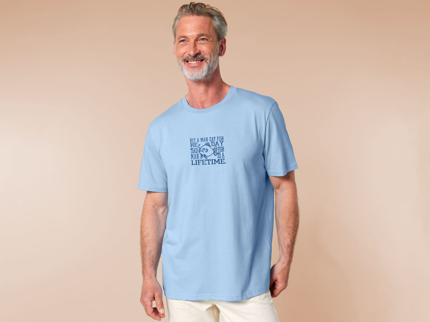 An embroidered blue t-shirt design of a funny cartoon fish and the text quote buy a man eat fish he day teach fish man to a lifetime.