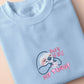 A blue t-shirt with an embroidered design of a cute chibi sloth holiding a board game dice surrounded by the funny quote Yes it is still my turn!
