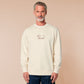A cream crew neck long sleeve sweater, with an embroidered brown thread design of a cute daschund dog looking concerend surrounded by the quote In This Economy?