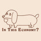 A cream crew neck short sleeve t-shirt, with an embroidered brown thread design of a cute daschund dog looking concerend surrounded by the quote In This Economy?