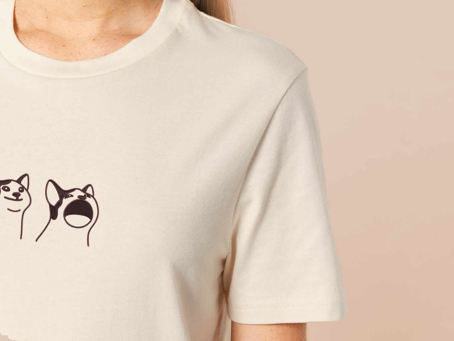 A cream crew neck short sleeve t-shirt, with an embroidered brown thread design of a cute popcat the cat meme reaction twitch emote