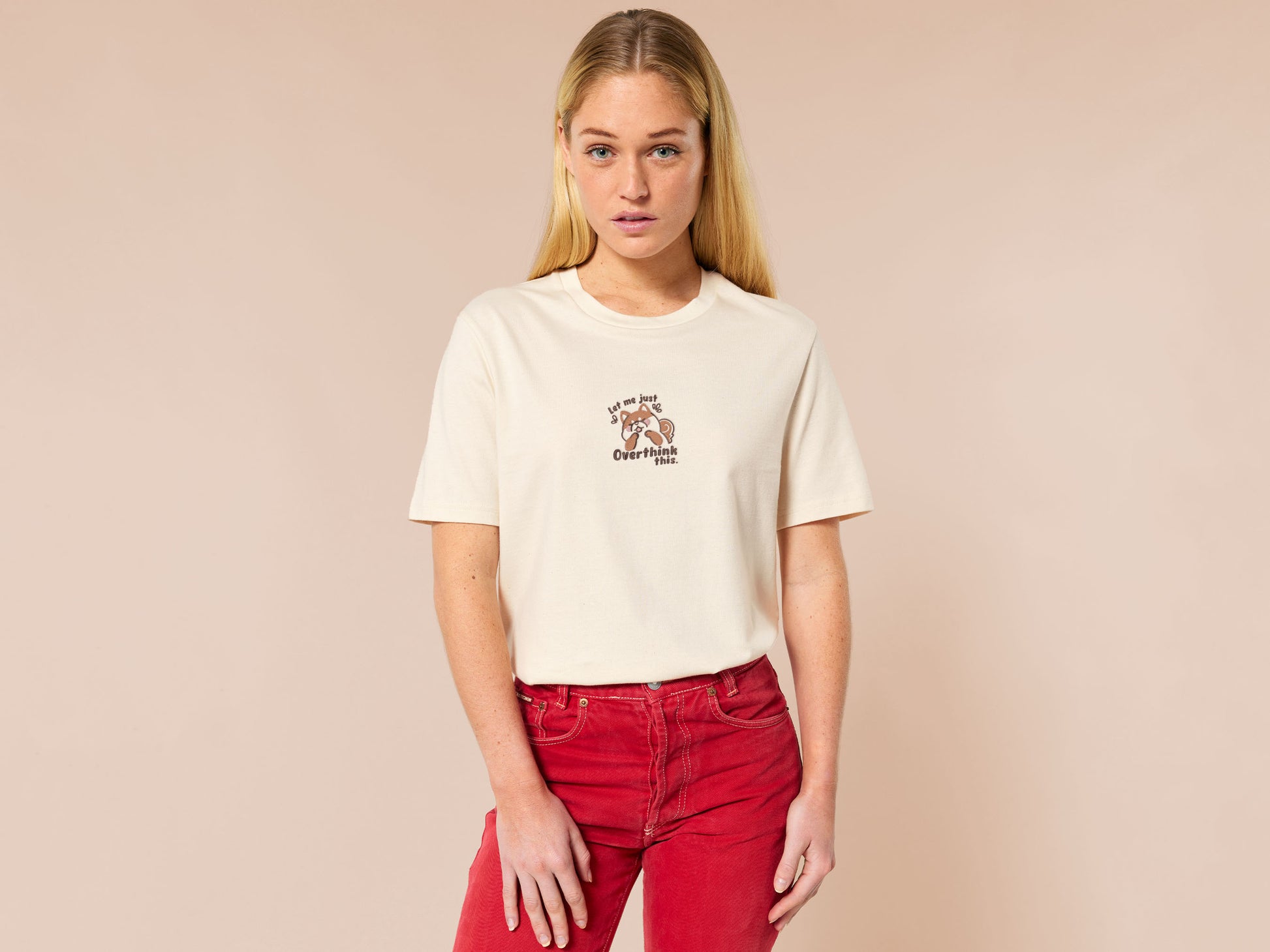 A cream crew neck short sleeve t-shirt, with an embroidered design of a cute shiba inu dog looking stressed surrounded by the quote Let Me Just Overthink This