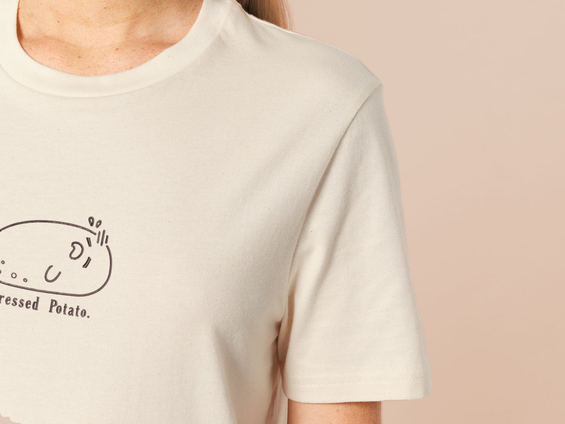 An embroidered cream t-shirt design of a funny stressed-out potato with the text underneath saying stressed potato.