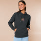 A dark grey crew neck long sleeve hoodie, with an embroidered cute chibi mimic chest holding a D20 dice rolled a one and the quote Looks fine to you.