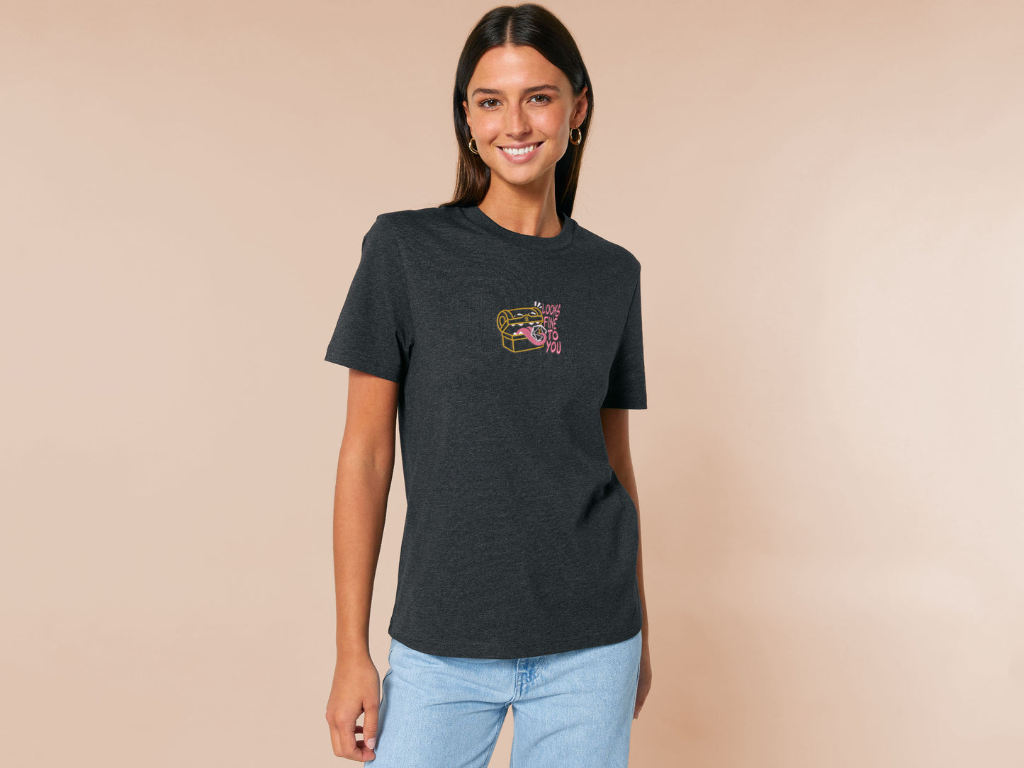 A dark grey crew neck short sleeve t-shirt, with an embroidered cute chibi mimic chest holding a D20 dice rolled a one and the quote Looks fine to you.