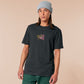 A dark grey crew neck short sleeve t-shirt, with an embroidered cute chibi mimic chest holding a D20 dice rolled a one and the quote Looks fine to you.