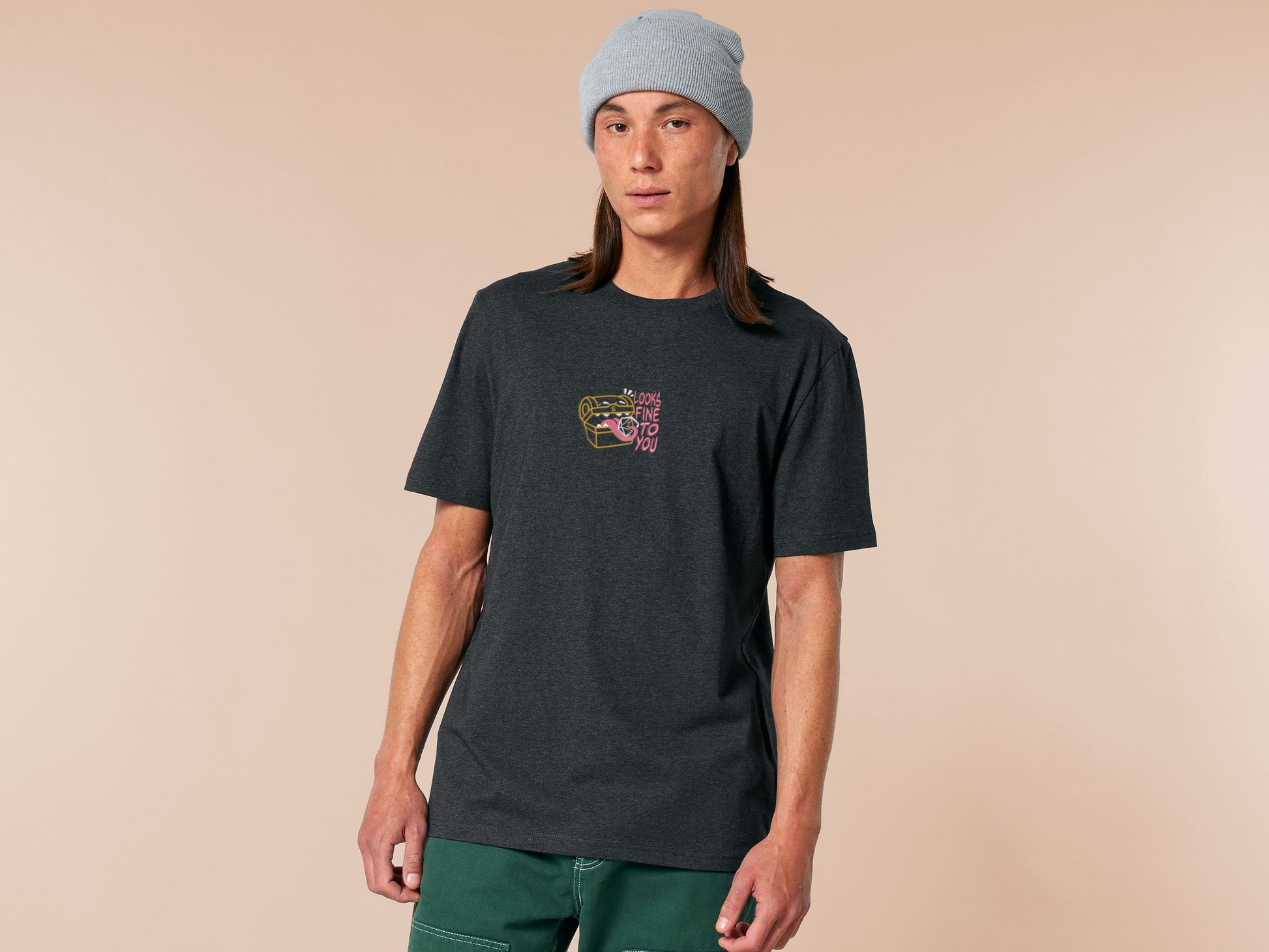 A dark grey crew neck short sleeve t-shirt, with an embroidered cute chibi mimic chest holding a D20 dice rolled a one and the quote Looks fine to you.