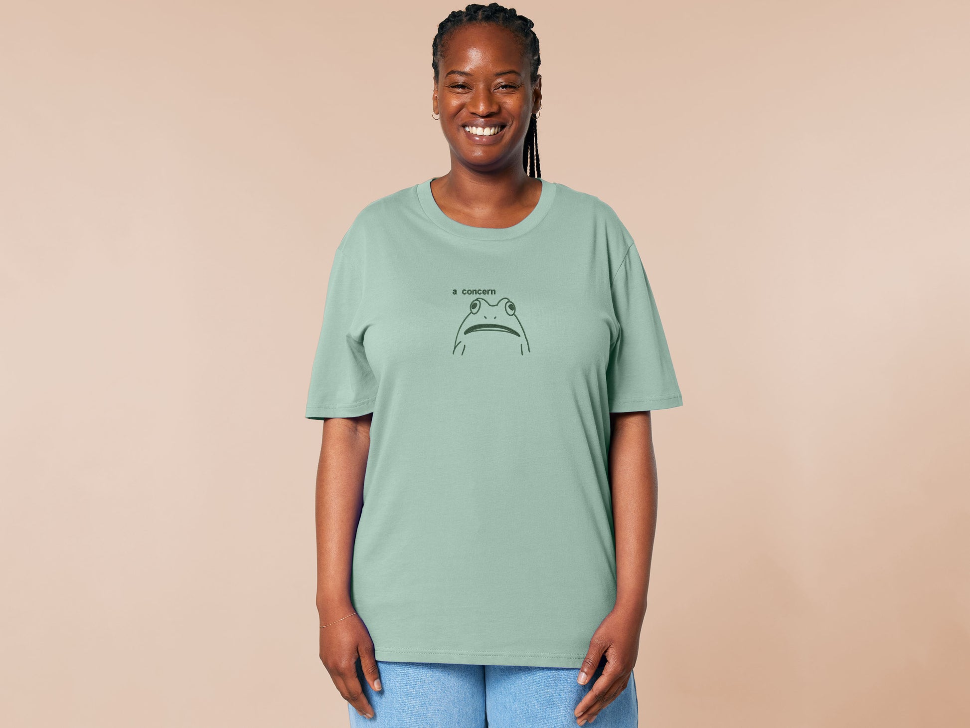 An embroidered green t-shirt design of a funny cartoon frog with the text a concern.