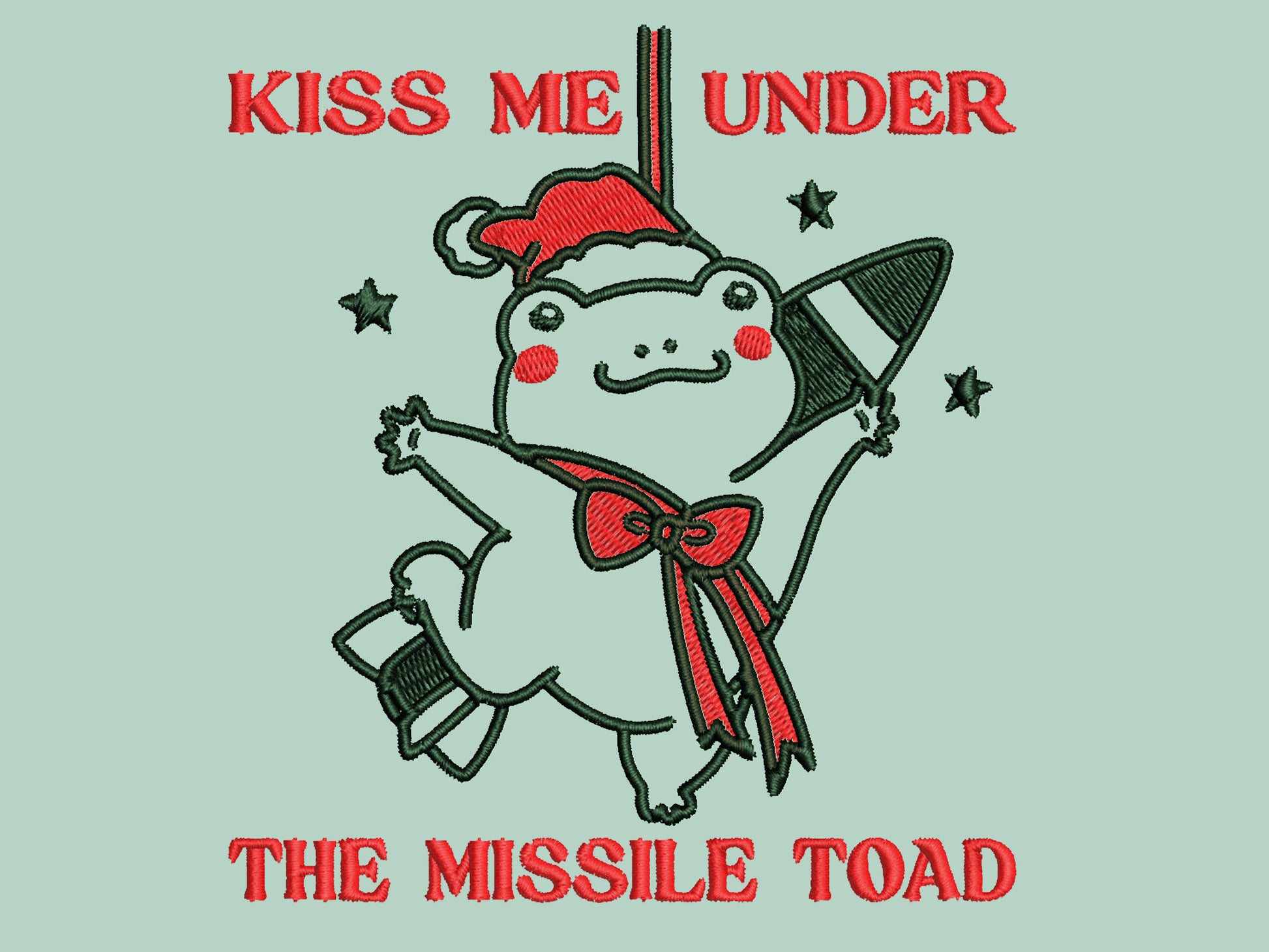 Green Christmas jumper with an embroidered design of the viral frog
meme Missile Toad, featuring a cute hanging chibi Christmas frog with the quote kiss me under the missile toad