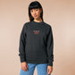 A dark grey crew neck long sleeve sweater, with an embroidered chibi mothman and the quote Live Lamp Lurk.