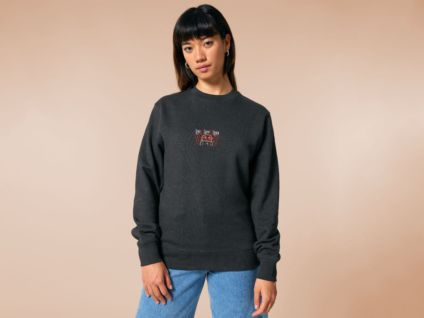 A dark grey crew neck long sleeve sweater, with an embroidered chibi mothman and the quote Live Lamp Lurk.