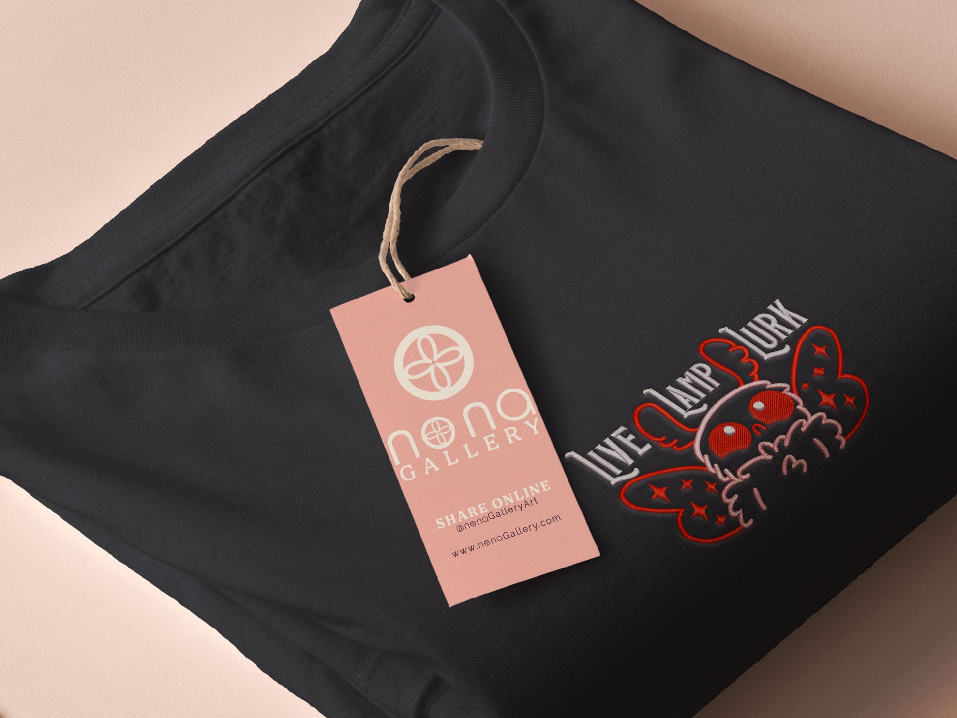 A dark grey crew neck short sleeve t-shirt, with an embroidered chibi mothman and the quote Live Lamp Lurk.