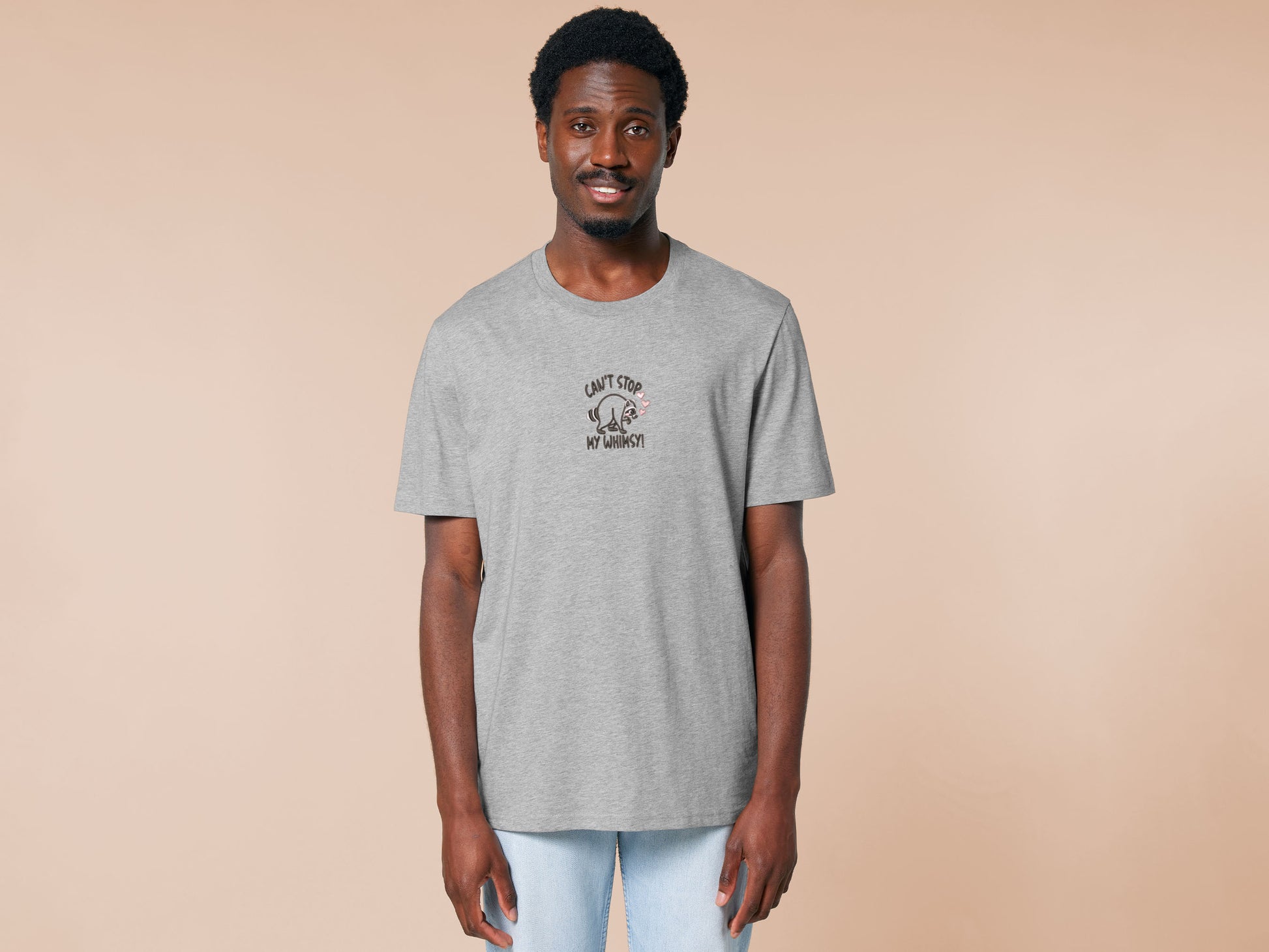 An Embroidered light grey t-shirt design of a cute Jimothy the viral disabled raccoon and the quote can't stop my whimsy!